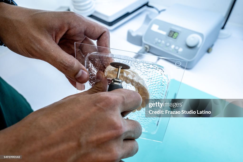 Close-up of a dental assistant/technician using a mini saw to cut a denture mold at dentistry laboratory