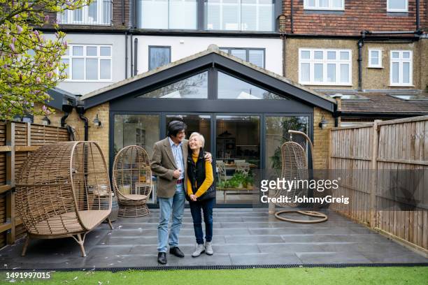 portrait candide d’un couple chinois heureux sur un patio moderne dans le jardin arrière - porte d'accès à la terrasse photos et images de collection
