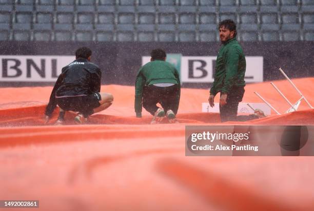 Grounds staff rush to cover the court as a rain storm hits during day fourteen of the Internazionali BNL D'Italia 2023 at Foro Italico on May 21,...