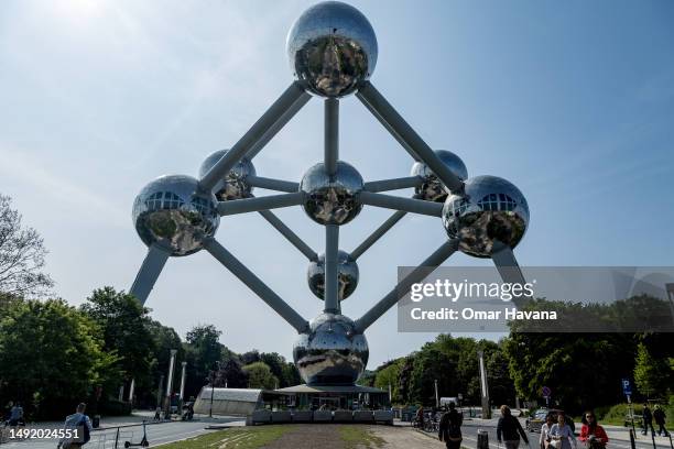 Tourists and locals walk on the esplanade leading to the Atomium, visible in the background on May 21, 2023 in Brussels, Belgium. Renovated between...