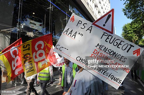 French car maker Peugeot PSA employee holds a placard as he takes part in a demonstration against the company planned layoffs and plant closing in...