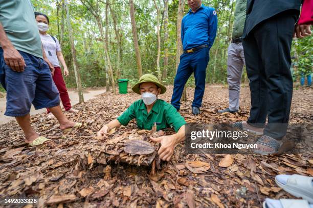 a guide demonstrating how a vietcong hide into the tunnel, cu chi tunnel is now touristic destination in ho chi minh city, vietnam - vietnam war stock pictures, royalty-free photos & images