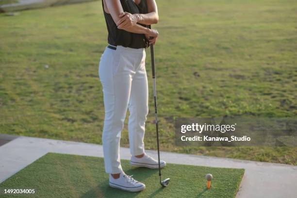 unrecognizable woman  suffering golfer elbow at driving range - amateur golfer stock pictures, royalty-free photos & images