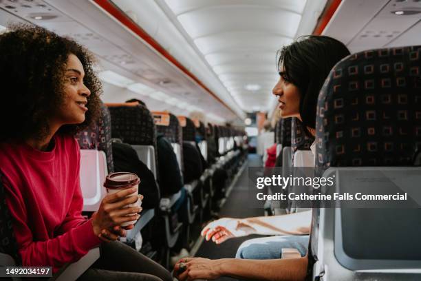 two woman drink coffee and have a light hearted chat on a plane - passenger point of view bildbanksfoton och bilder