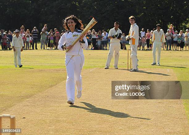 In this handout image provided by LOCOG, Torchbearer 001 Joanna Hyams carries the Olympic Flame on the wicket at Pinner Cricket Club in Harrow at the...