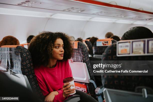 a young woman looks pensive on a plane - pressure airplane stock pictures, royalty-free photos & images