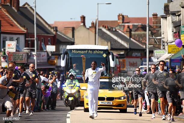 In this handout image provided by LOCOG, Musician Labrinth carries the Olympic Flame on the Torch Relay leg between Harrow and Brent during Day 68 of...