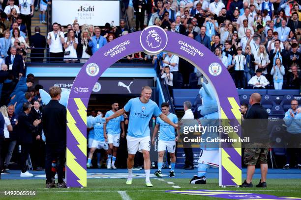 Erling Haaland of Manchester City shakes hands with Moonchester and Moonbeam the Mascots of Manchester City as they walk out of the tunnel for the...