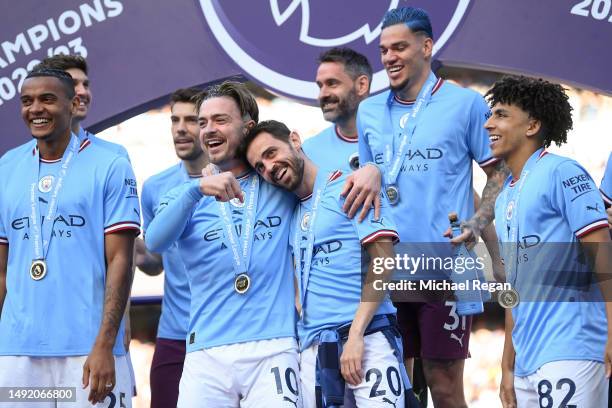 Jack Grealish of Manchester City embraces Bernardo Silva whilst on the stage with teammates during the Trophy Ceremony after the Premier League match...