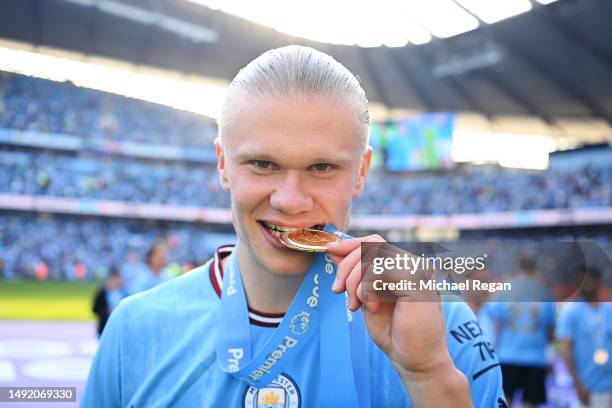 Erling Haaland of Manchester City bites their Premier League Winners Medal following the Premier League match between Manchester City and Chelsea FC...