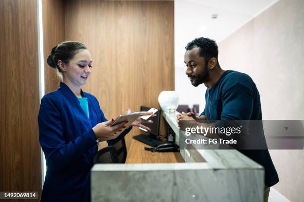 recepcionist im gespräch mit einem patienten in einer medizinischen klinik - salon reception stock-fotos und bilder