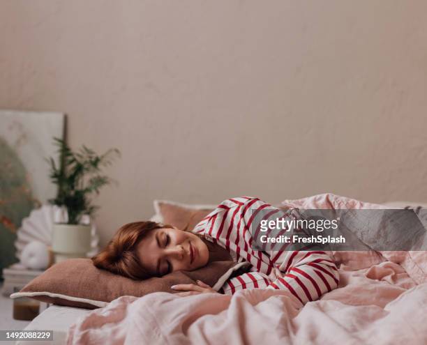 beautiful ginger woman lying in her bed,  sleeping in on a weekend - woman sleeping stock pictures, royalty-free photos & images