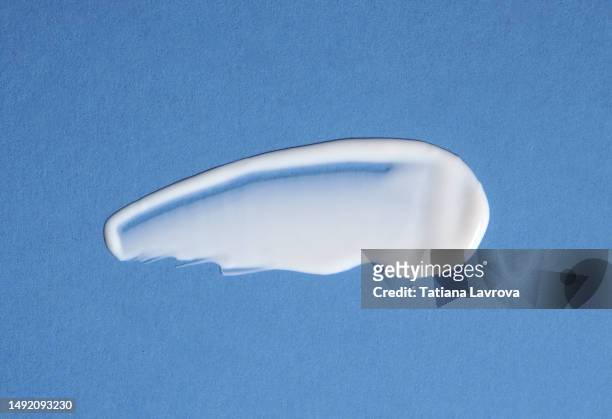 swatch of white face cream on blue background. smear of moisturizing beauty product for healthy skin. - smudged stock pictures, royalty-free photos & images