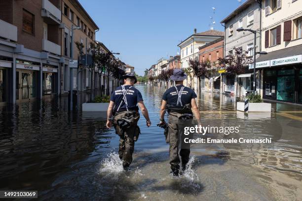 Two Italian Coast Guard officers wade a flooded street on May 21, 2023 in Conselice, near Ravenna, Italy. Fifteen people have died and forty thousand...