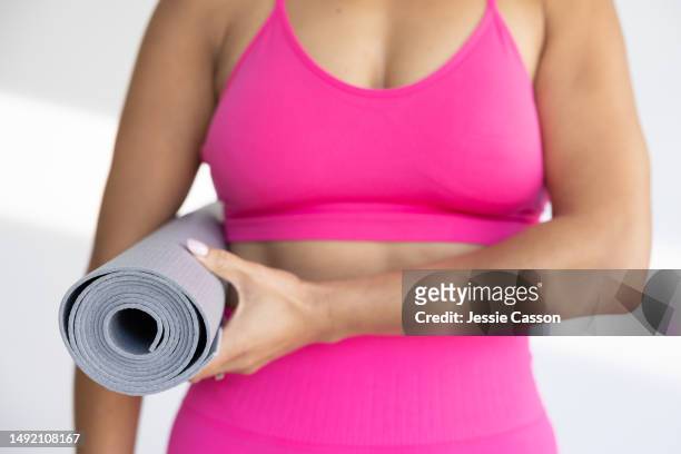 woman's torso wearing pink exercise wear and carrying rolled up yoga mat - woman torso stock pictures, royalty-free photos & images