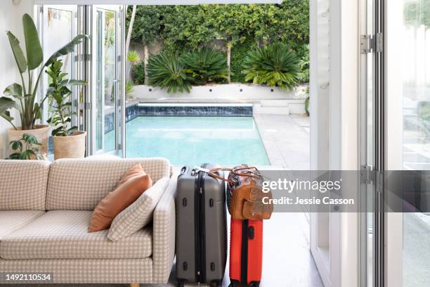 sofa and packed suitcases inside in front of swimming pool - airbnb stockfoto's en -beelden