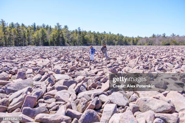 former lake - current rock stone area. hispanic couple travelling in mountain rock area among stone run. hickory run boulder field, poconos, pa - pennsylvania nature stock pictures, royalty-free photos & images