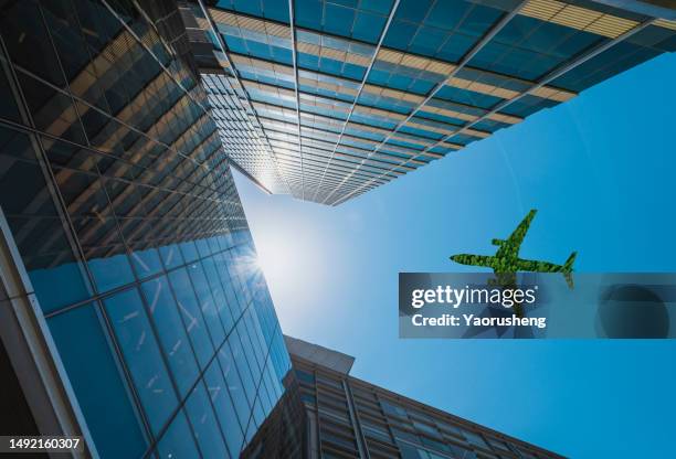 low angle view of green airplane flying over business office building - low flying aircraft stockfoto's en -beelden