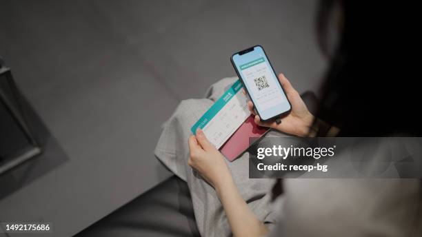 businesswoman checking her digital boarding app on smart phone and her plane ticket - leaving card stock pictures, royalty-free photos & images