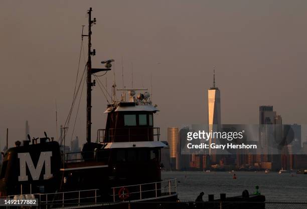 The sun sets on the skyline of lower Manhattan and One World Trade Center in New York City as a tugboat passes by on May 21 in Bayonne, New Jersey.