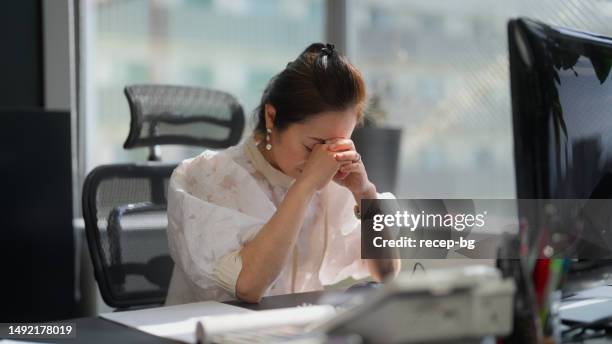 businesswoman feeling stressed in office - com as mãos na cabeça imagens e fotografias de stock