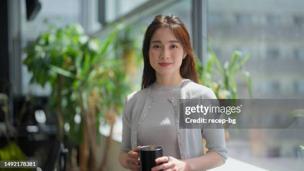 portrait of cheerful beautiful businesswoman in modern green office with lots of plants - japanese people stock pictures, royalty-free photos & images