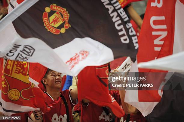 Local Manchester United fans cheer as they wait for the start of a friendly match against Shanghai Shenhua in Shanghai Stadium in Shanghai on July...