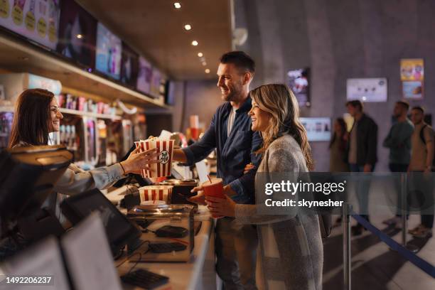 happy couple buying popcorn and drinks in cinema. - film industry stock pictures, royalty-free photos & images