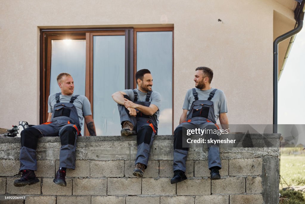 Team von glücklichen Arbeitern, die sich in einer Pause auf der Terrasse unterhalten.