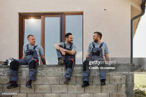 team of happy manual workers talking on a break at patio. - empreiteiro de reparações imagens e fotografias de stock