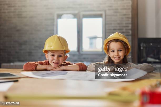 glückliche kleine architekten mit schutzhelmen bei der renovierung des hauses. - rebuilding stock-fotos und bilder