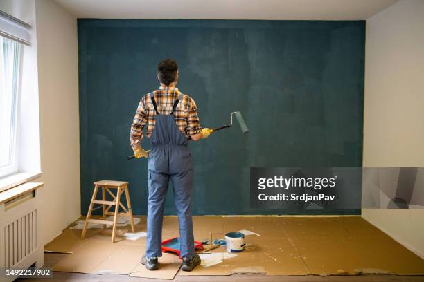 house painter observing the wall he paints - handyman overalls stock pictures, royalty-free photos & images