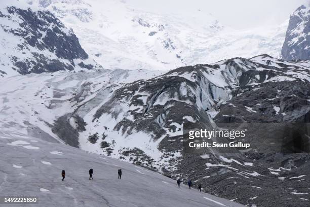 Alpinists walk across the receding Morteratsch glacier on May 21, 2023 near Pontresina, Switzerland. On June 18 Swiss voters will go to the polls to...