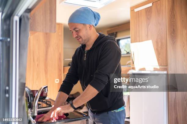 man washing dishes i̇n the kitchen of his caravan - trailer home stock pictures, royalty-free photos & images