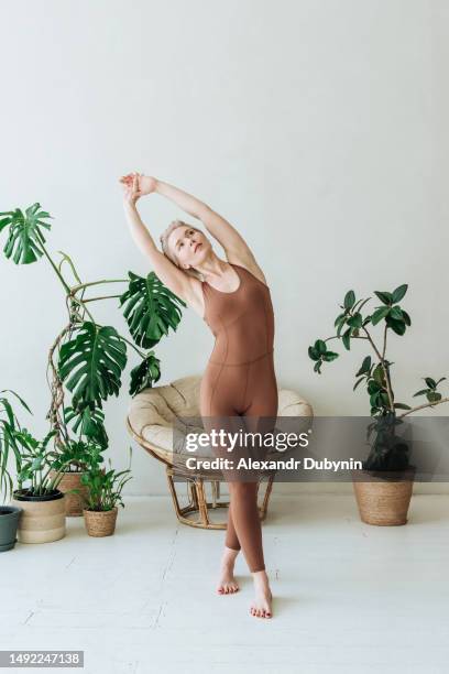 beautiful woman doing yoga at home, standing among indoor plants. yoga concept - boa postura imagens e fotografias de stock