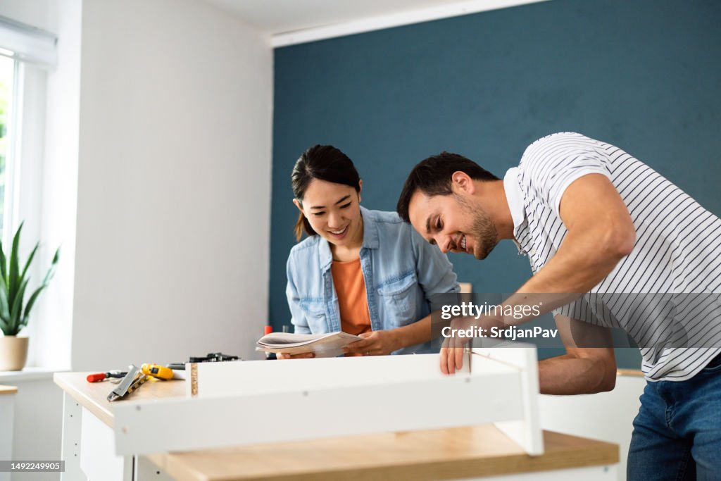 Casal montando móveis juntos em seu novo apartamento