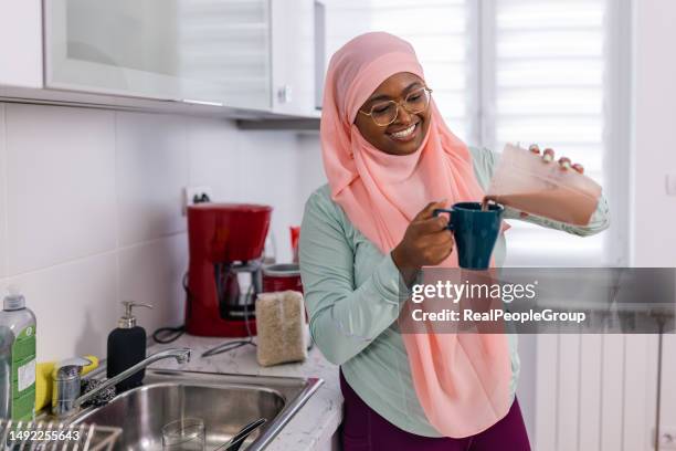 young muslim woman prepares and pours a chocolate protein smoothie with precision - protein stock pictures, royalty-free photos & images