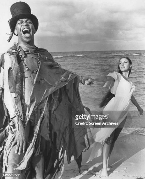 Geoffrey Holder as Baron Samedi poses on beach with Jane Seymour as Solitaire for the 1973 James Bond film 'Live and Let Die' .