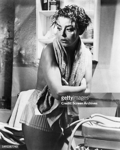 Janet Munro stands over sink with wet hair topless with towel around neck in a scene from the 1962 sci-fi movie 'The Day The Earth Caught Fire' .