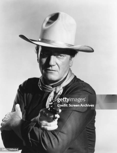 John Wayne points gun in a publicity portrait for the 1962 John Ford western 'The Man Who Shot Liberty Valance'.