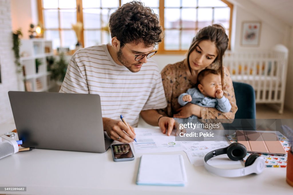 Giovane famiglia con il bambino sveglio che va oltre le finanze a casa