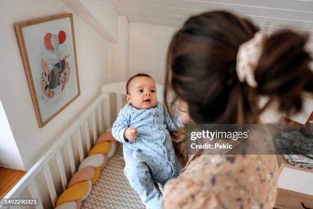mutter legt ihr baby in babybett - baby crib stock-fotos und bilder