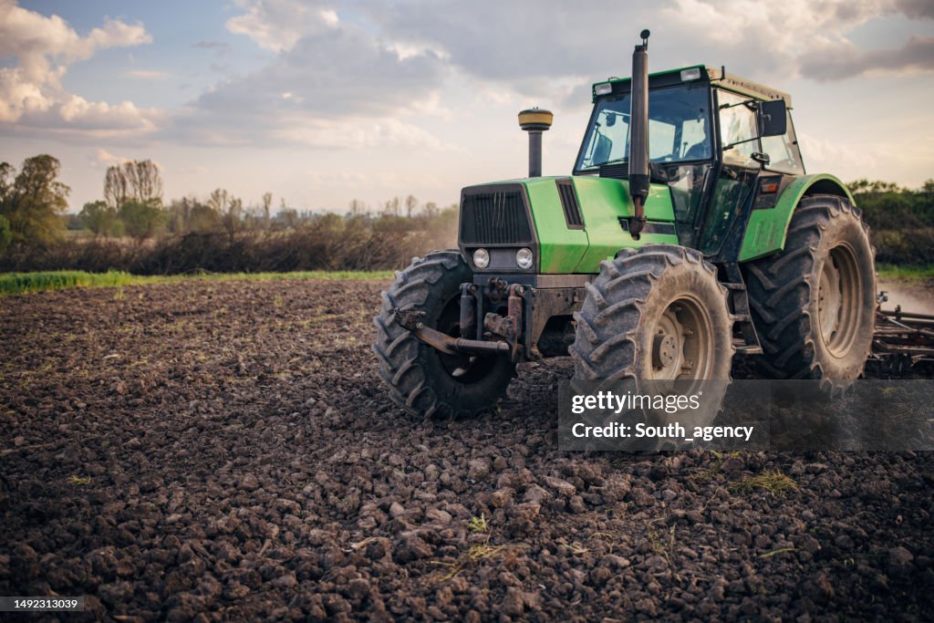 Agricultor mayor conduciendo un tractor en el campo agrícola