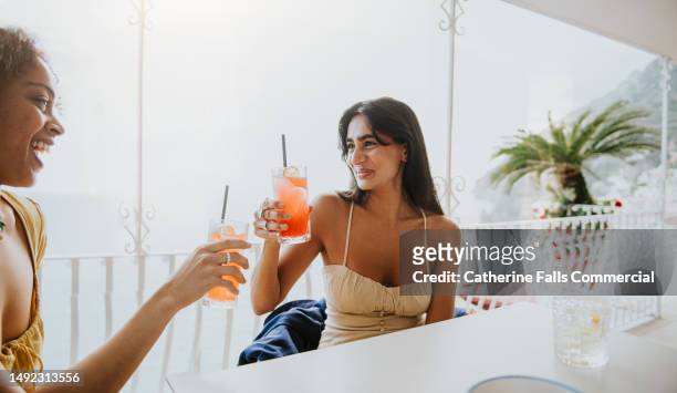 female friends enjoy a cocktail in an al fresco dining experience - holiday cocktail party stockfoto's en -beelden