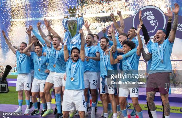 Manchester City captain Ilkay Gundogan lifts the Premier League trophy in front of team mates after the Premier League match between Manchester City...