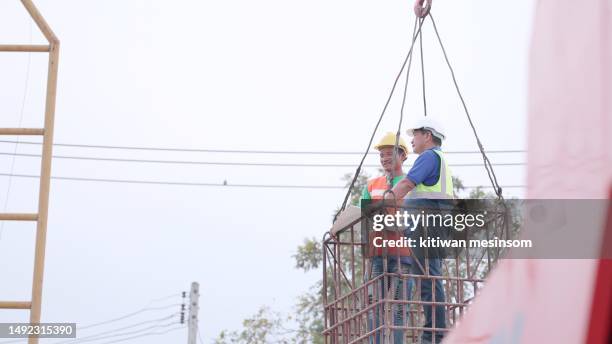 contractor and foreman in safety uniform standing on the lift to check the progress of the buildings at construction site. engineer and partners in construction business and working together on construction of buildings or housing projects. - picking up stock pictures, royalty-free photos & images