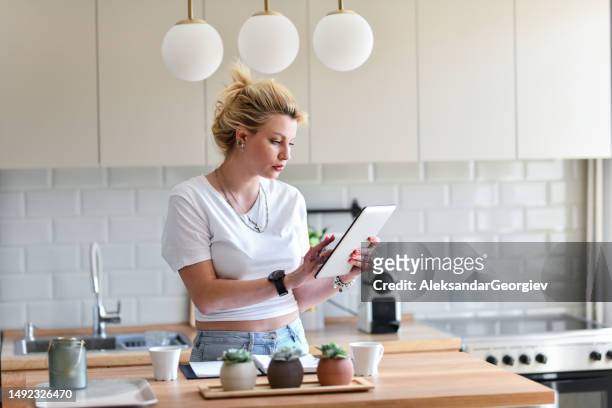 blonde frau sucht im internet nach einem richtigen rezept - lady cooking confused stock-fotos und bilder