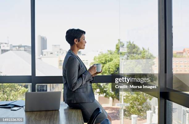 thoughtful businesswoman having coffee in modern office - business frau profil kurze haare stock-fotos und bilder