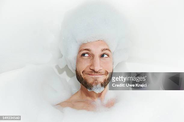 portrait of man in bath tub, foam on head - bubbelbad stockfoto's en -beelden