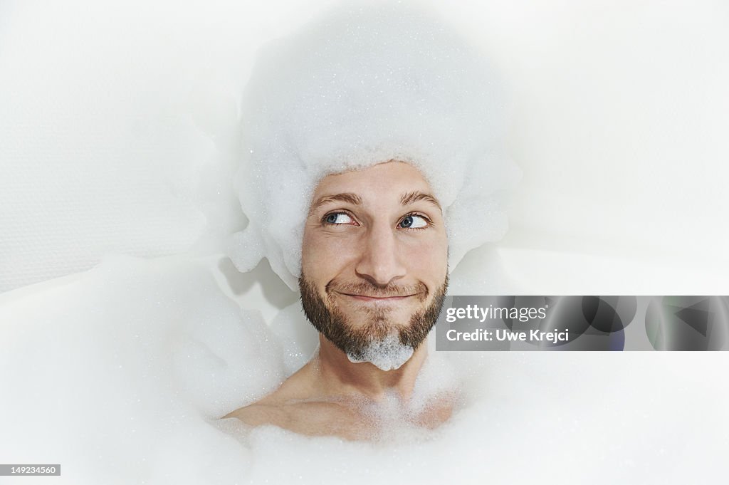 Portrait of man in bath tub, foam on head